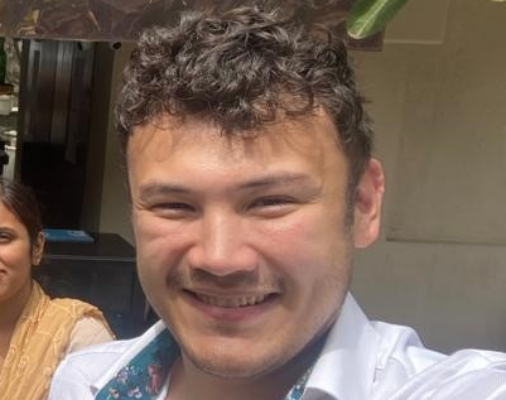 Smiling man in suit and tie standing outdoors